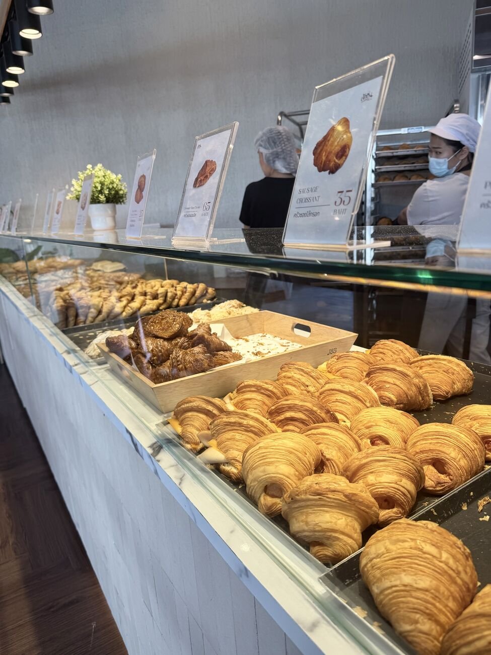 Fresh trays coming out — sausage croissant ฿35, ham &amp; cheese ฿65 on the cards.