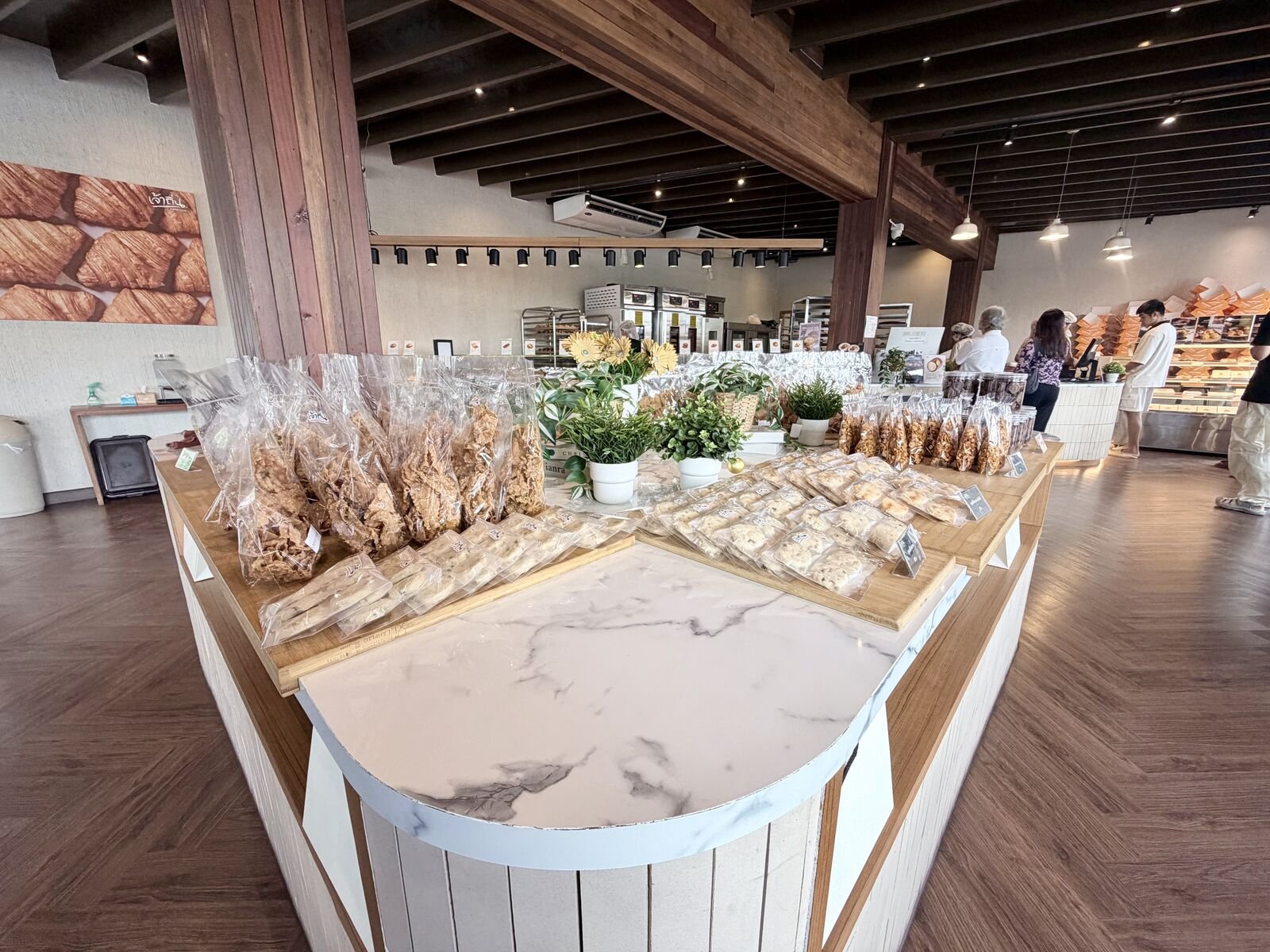 Customers at the counter. Packaged cookies and granola line the island; the bakery racks are behind.