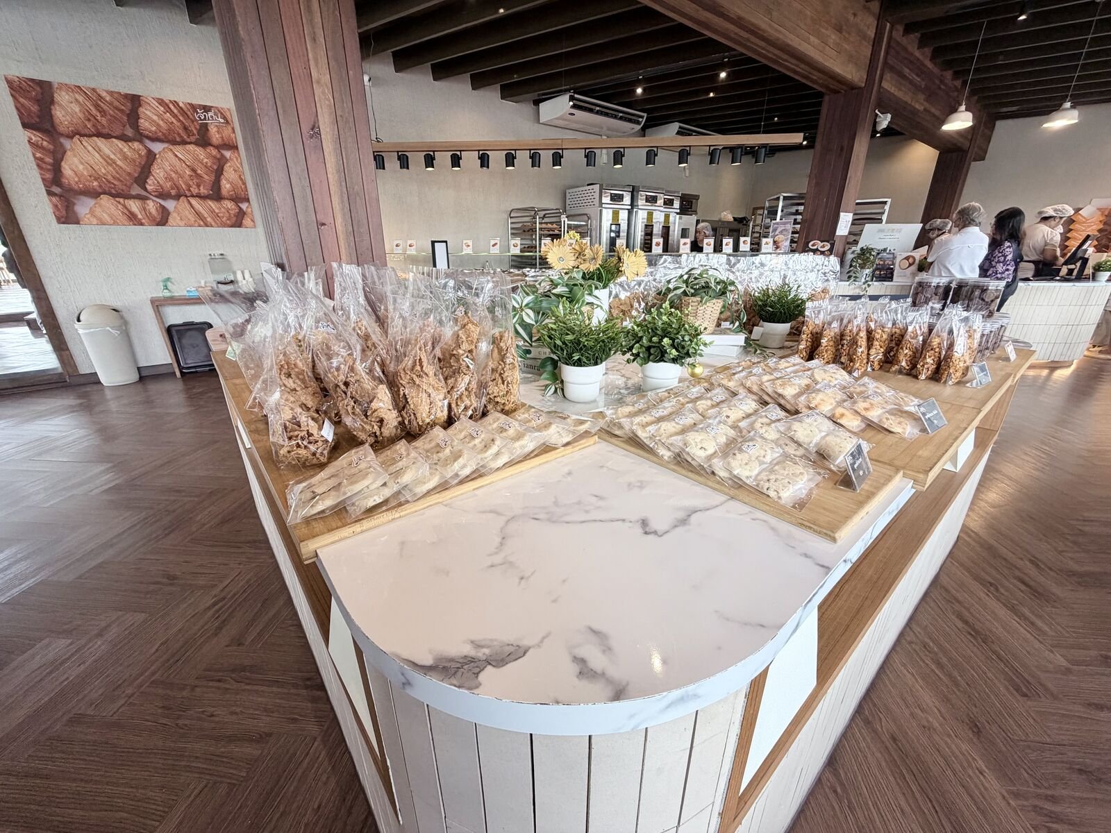 Interior of a spacious Bangkok bakery-café with timber beams and a marble counter